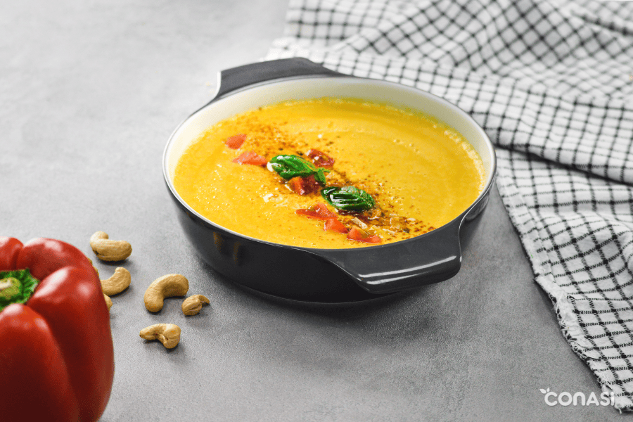 crema thai decorada con anacardos, trocitos de pimiento y albahaca