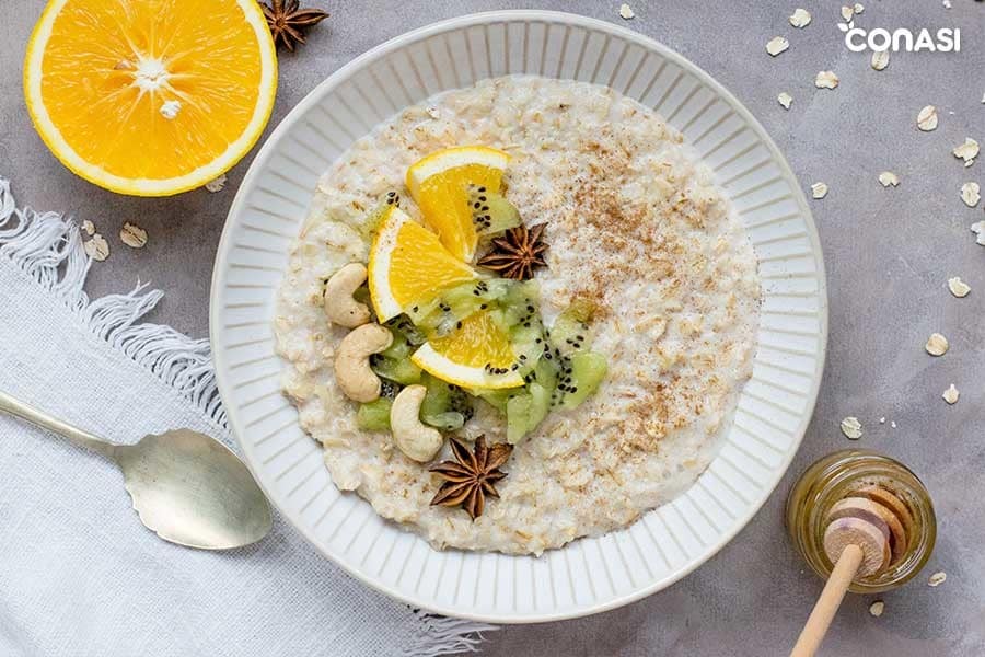 Un plato con porridge de copos de avena con fruta y anacardos.