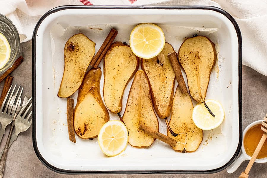 Peras cocidas en una bandeja de horno con canela y limón.