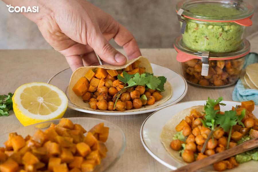 Una mano cogiendo tacos vegetarianos