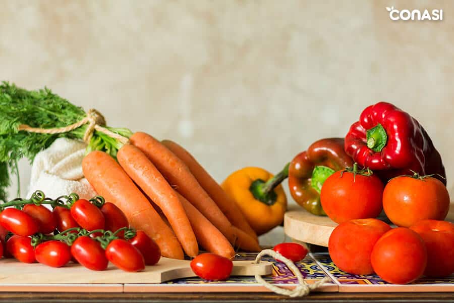 Cómo cocinar hortalizas - zanahorias, tomates y pimientos en una mesa Cómo cocinar hortalizas - zanahorias, tomates y pimientos en una mesa