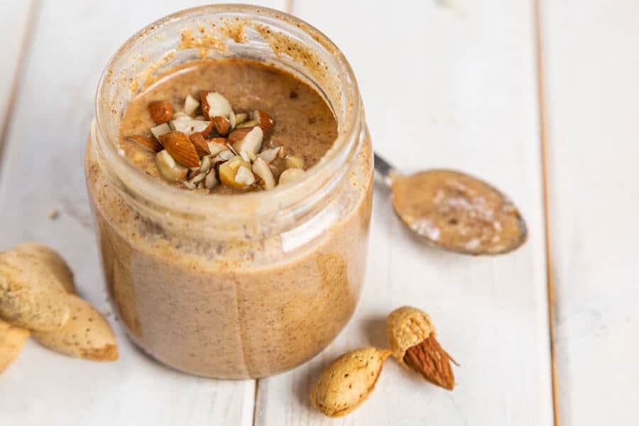 Tarro de cristal con mantequilla de almendras y trocitos de almendras