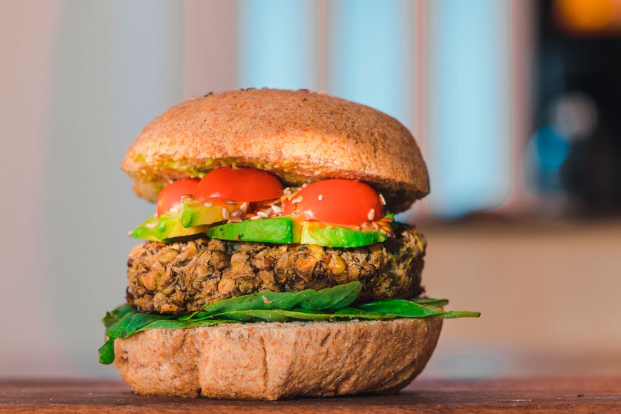 Hamburguesa vegana de lenteja con pan de hamburguesa, aguacate y verduras.