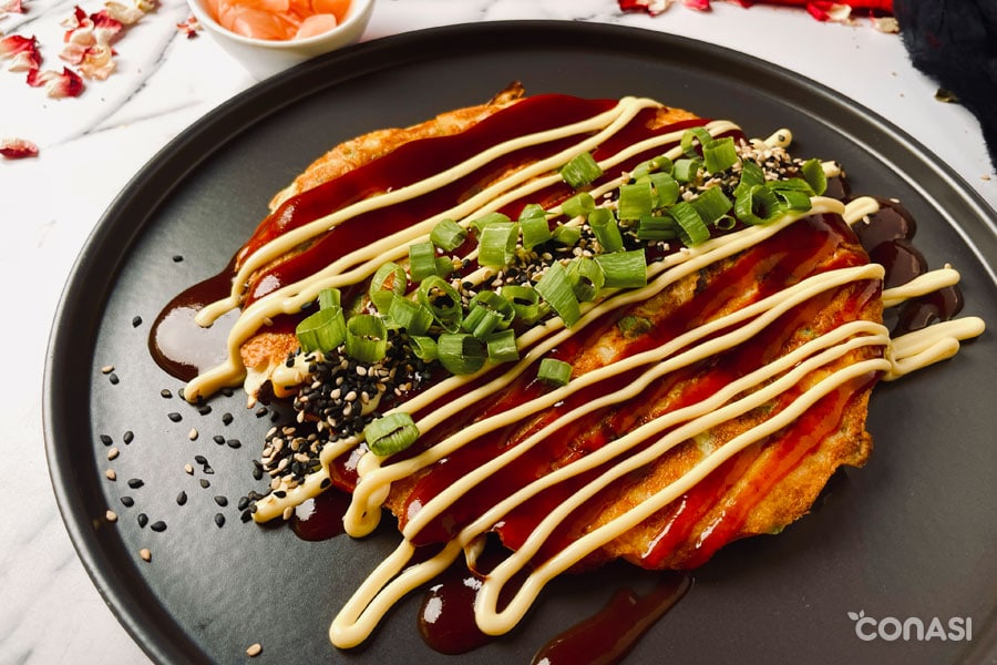 okonomiyaki emplatado con salsas y cebolleta