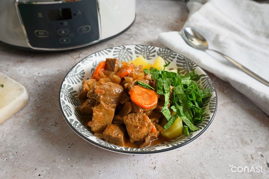 goulash vegano servido en un plato con patata y espinacas