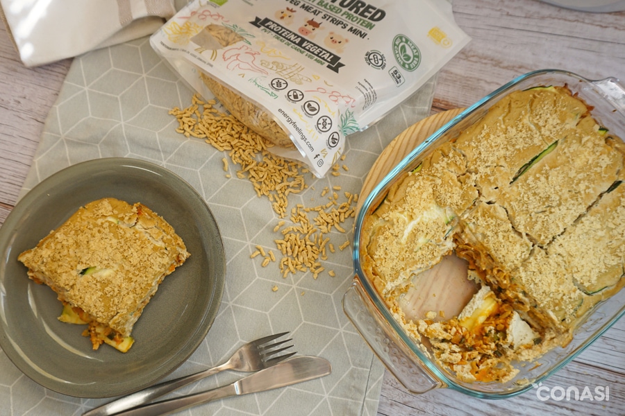 lasaña de calabacín en plato, con fuente y la proteína vegana
