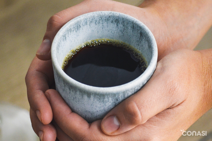 manos con una taza llena de café pour over