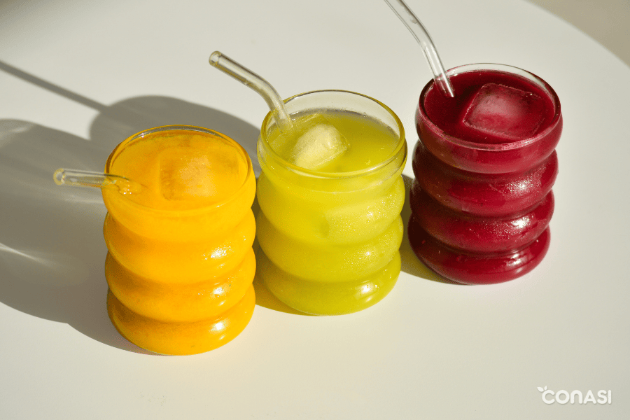 vasos con zumos de colores servidos con hielo y pajita de vidrio vasos con zumos de colores servidos con hielo y pajita de vidrio