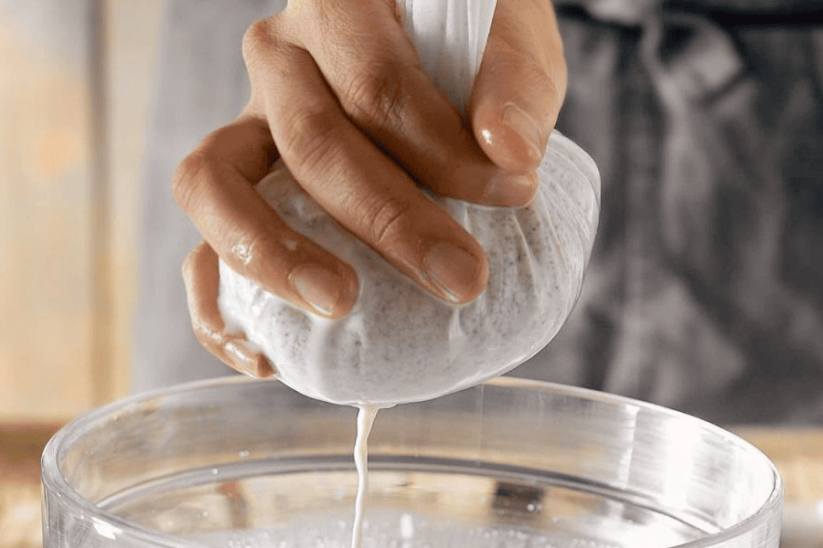 elaborando bebidas vegetales con bolsa de algodón apretando la bolsa de algodón para obtener bebida vegetal